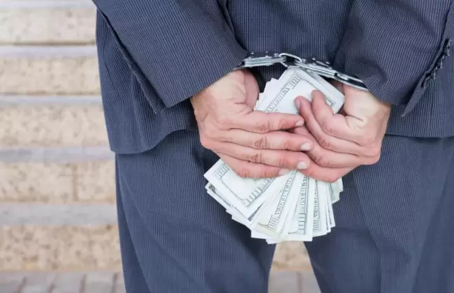 businessman-hands-in-handcuffs-holding-us-dollars